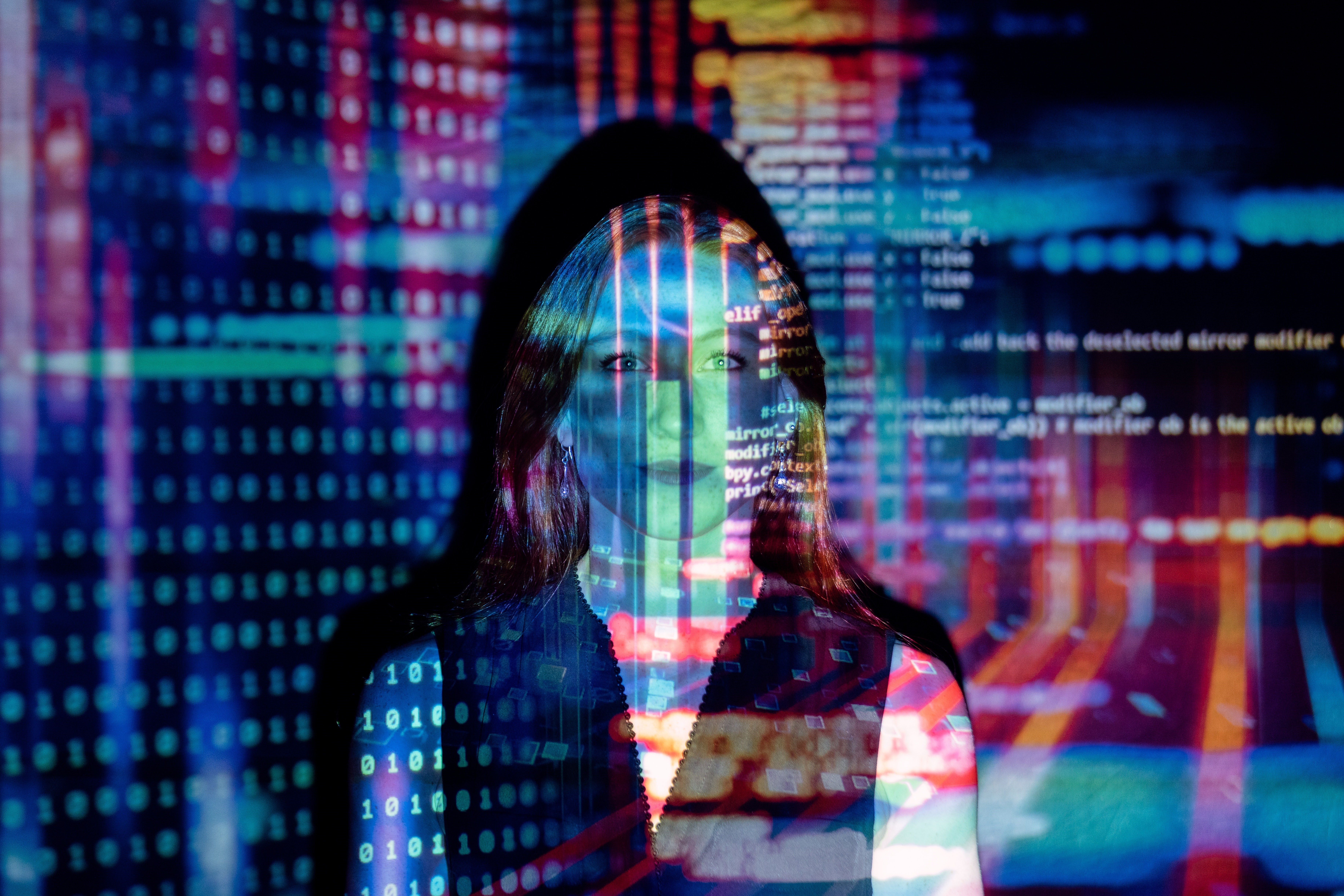 Image of a woman standing in front of a projection of what appears to be software code.