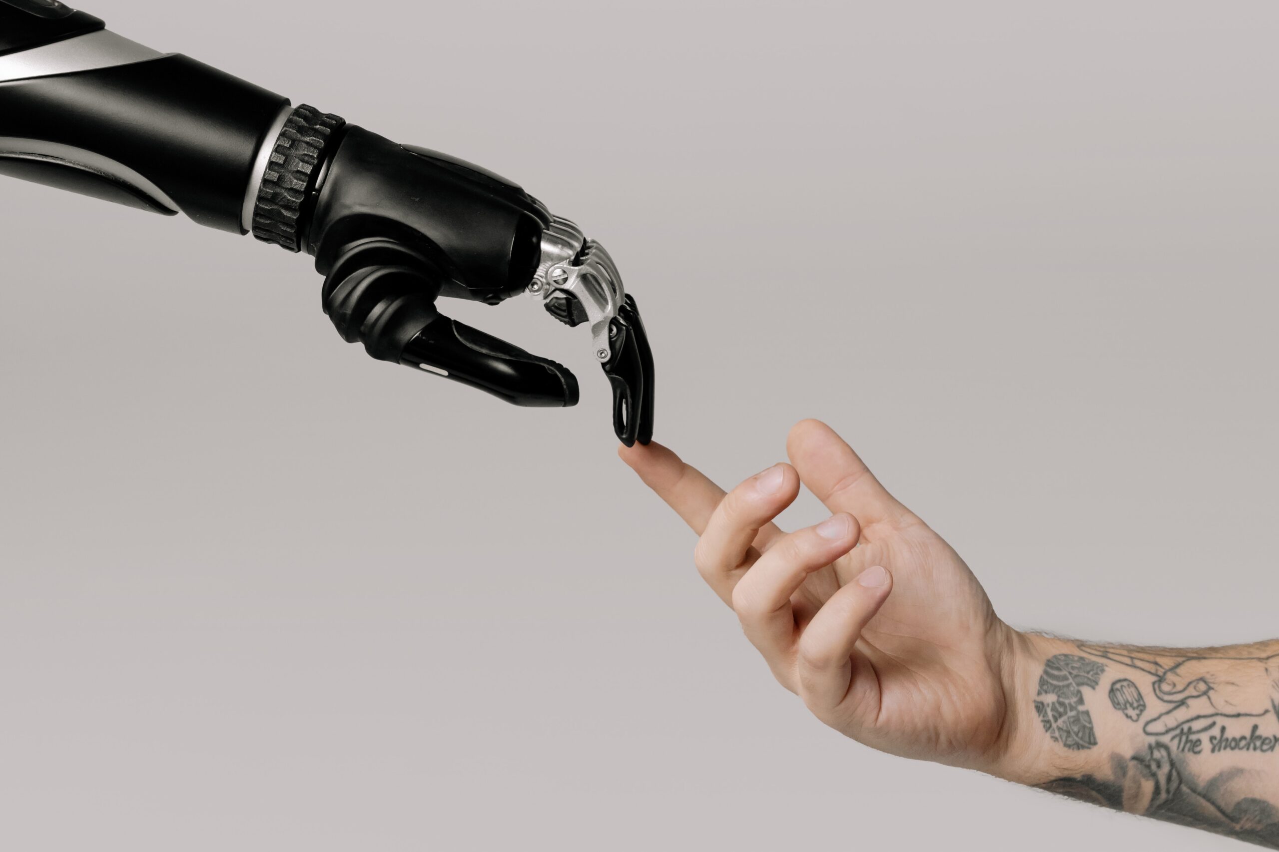 Image of a robotic arm and a human arm, fingertips touching.
