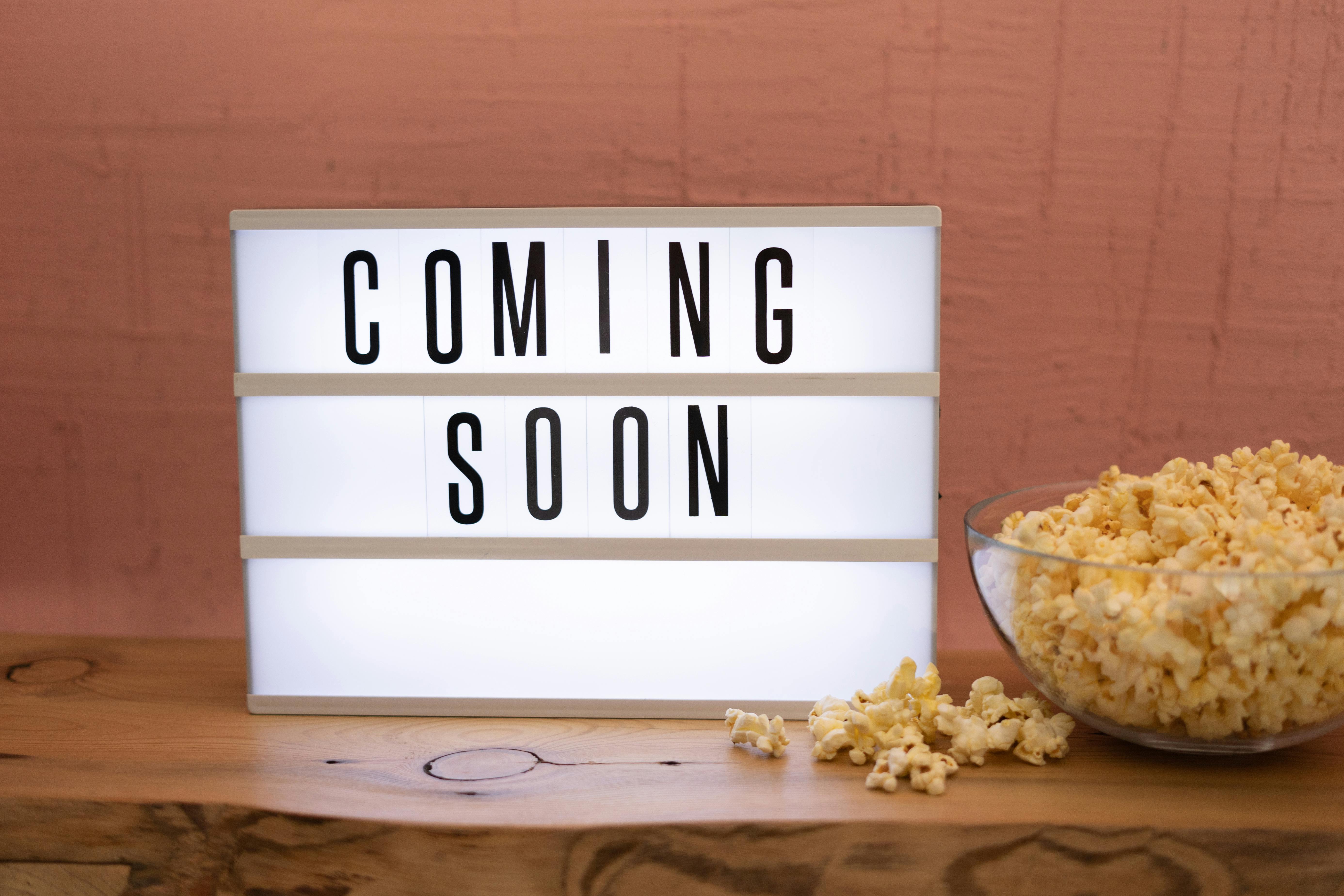 "Coming soon" sign with a bowl of popcorn.
